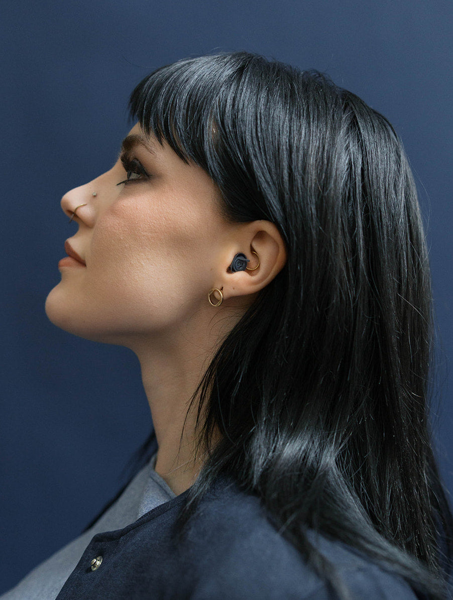 girl wearing earpeace everyday earplug in navy #color_navy