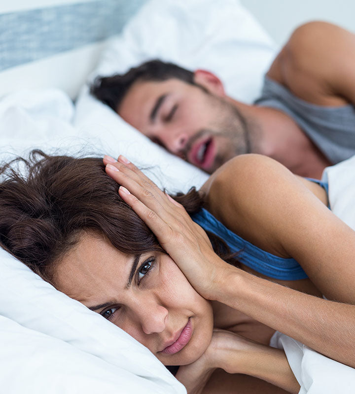 woman lying next to her snoring husband
