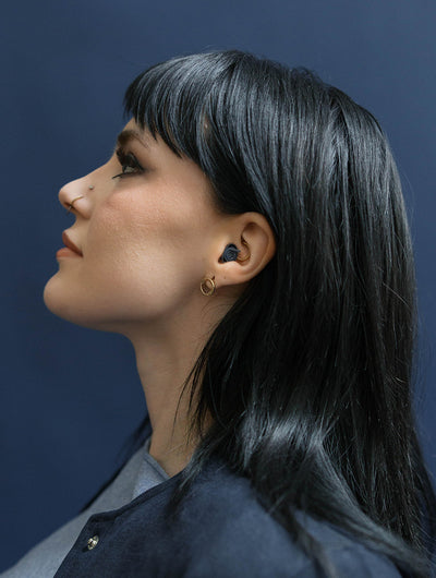 girl wearing earpeace everyday earplug in navy #color_navy